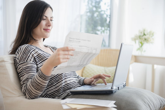 Caucasian woman paying bills using laptop