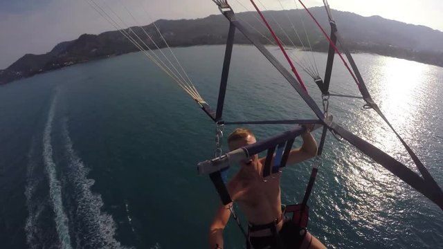 Parasailing Man Flying with GoPro in Blue Sky over Sea on Vacation