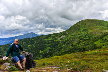 Naklejka premium Portrait of young men tourist who stopped to the rest in Carpathian mountains, summertime journey