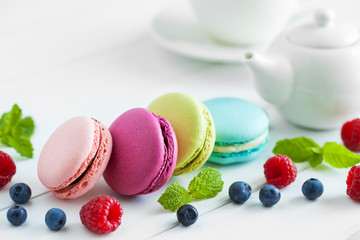 Macaroons, raspberries, blackberries and teapot with cup of tea
