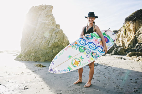 Caucasian woman carrying surfboard at beach