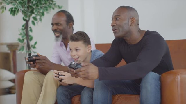  3 Male generations of happy family playing video games together at home