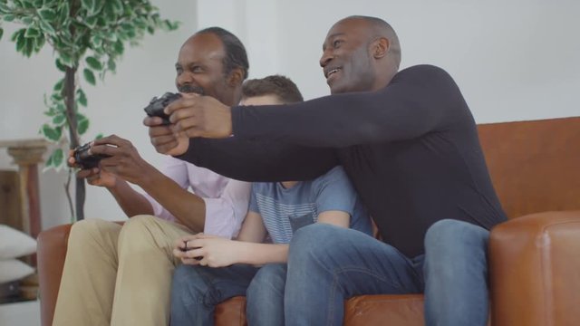  3 Male generations of happy family playing video games together at home