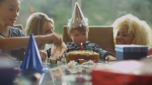  Little boy celebrating his birthday with a cake & happy family & friends