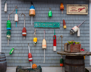 Coastal iconic northeastern USA items including lobster buoys, seafood signs, lobster traps and barrels on shingled building