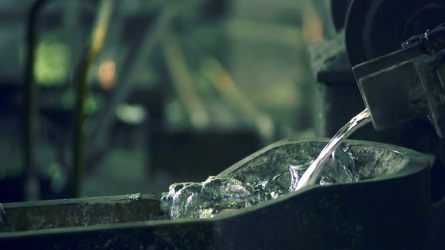 Liquid melt metal flows from the melting furnace, blurred background, close-up