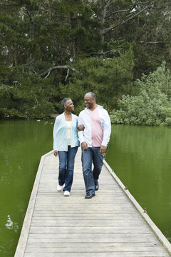 Smiling African American couple standing on pier at lake
