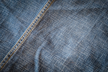 Texture of dark fabric blue jeans textile with seam. Close up detail background