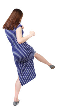 skinny woman funny fights waving his arms and legs. Isolated over white background. The brunette in a blue striped dress stands sideways beats foot.