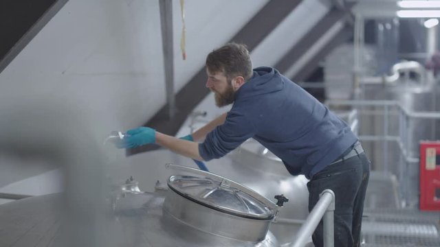 Worker in a brewery checking the equipment as he makes the product