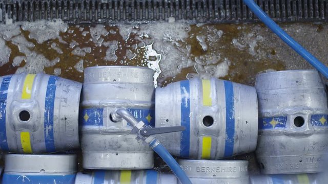  Overhead view of barrels of beer being filled with a hose in a brewery