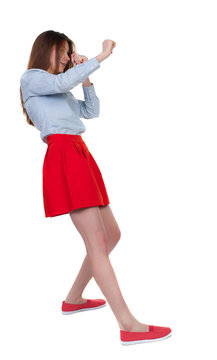 skinny woman funny fights waving his arms and legs. Isolated over white background. Long-haired brunette in red skirt leaned protected from impact.