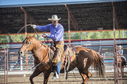 Older Caucasian cowboy throwing lasso at rodeo