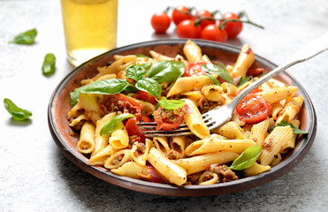 pasta with meat and basil on a plate on a gray background