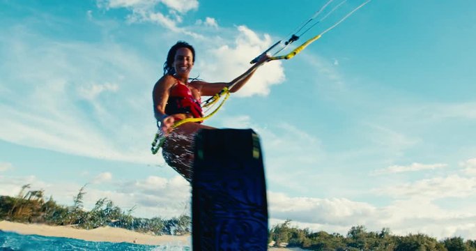 Beautiful young woman kiteboarding at sunset in slow motion, active lifestyle extreme sport