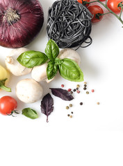 black pasta and fresh basil, mushrooms, cherry tomatoes, onions, peppers on a white background