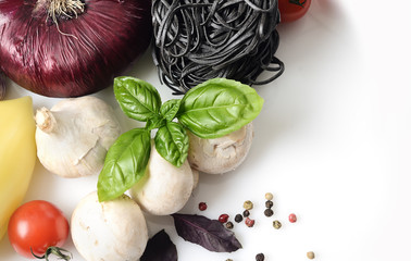 black pasta and fresh basil, mushrooms, cherry tomatoes, onions, peppers on a white background