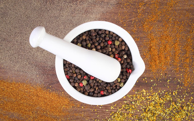 Colorful pepper in mortar and powdery pepper on rustic boards