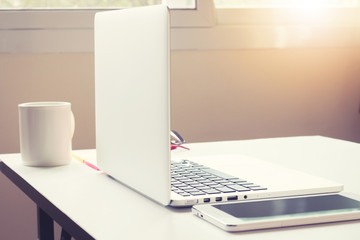 Office desk with laptop smart phone and business office backgrou