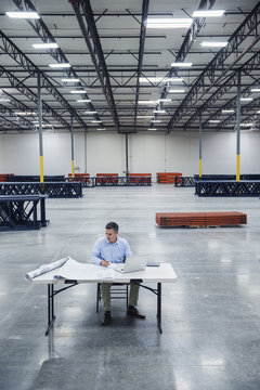 Caucasian architect reading blueprints in warehouse