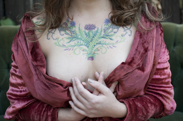 Caucasian woman in bathrobe displaying chest tattoos