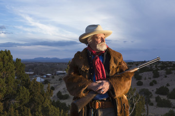 Man dress wild west style holding rifle in prairie