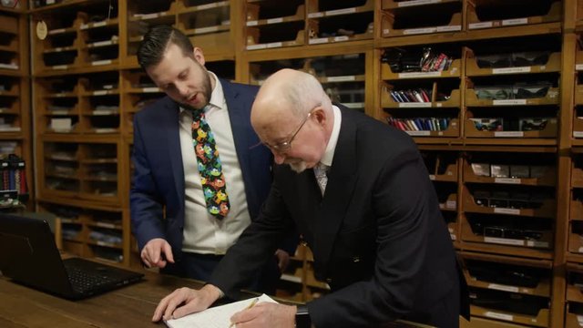  Shopkeepers in man's clothing store standing behind counter looking at accoun