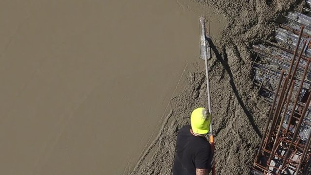 Top view of unrecognizable construction site workers smoothing and level cement coat in building site.