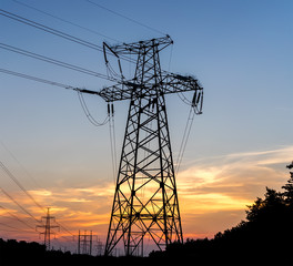 Electric pole connect to the high voltage electric wires on sunset sky background.