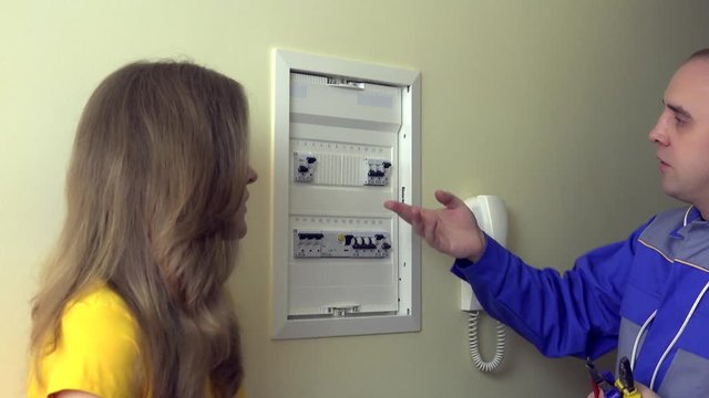Electrician man explain for housewife woman client how to use circuit breaker box