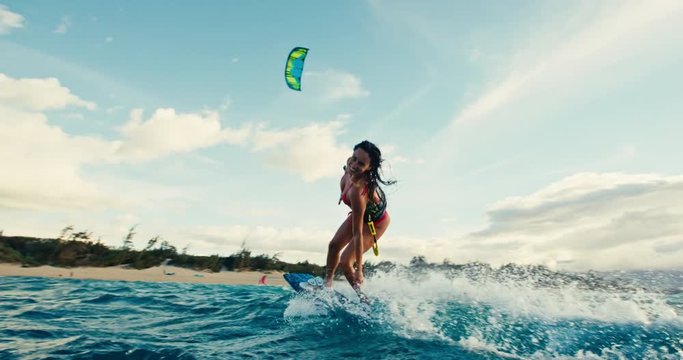Beautiful young woman kiteboarding at sunset in slow motion, active lifestyle extreme sport
