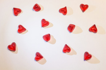 illuminated small hearts with shadows on white background; heart-shaped jelly candy like pieces of glass