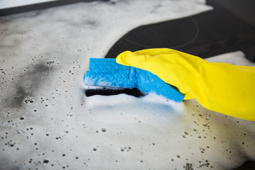 A woman washes a plate, ceramic hob