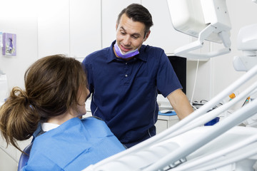 Obraz premium Male Dentist Communicating With Female Patient In Clinic