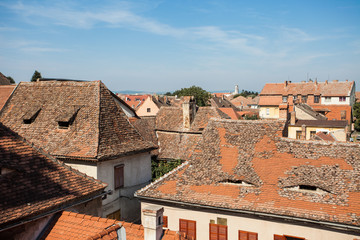 Fototapeta na wymiar Aerial view of tiled rooftops. A house with attic windows like with smiling eyes