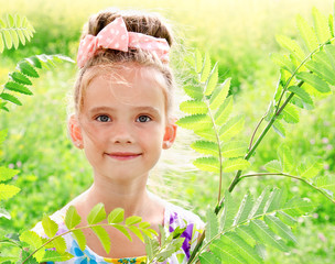 Adorable smiling little girl on the meadow in summer day
