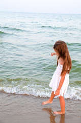 Fototapeta na wymiar Adorable little girl is walking on the sea coast