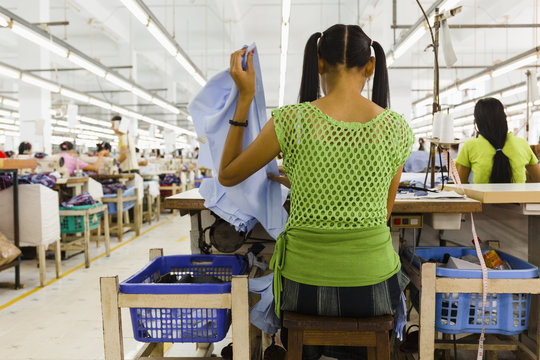 Female Worker Sewing Clothes In Garment Factory