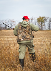 Hunter moving with shotgun looking for prey.