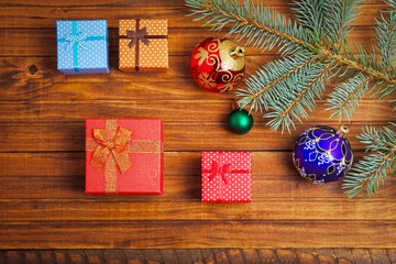 Fototapeta na wymiar Christmas gifts, fir-tree branch and christmas toys on wooden background
