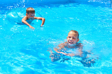 Girl and boy swimming into resort pool