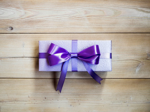Purple gift box on wooden board. Copy space. Holidays concept