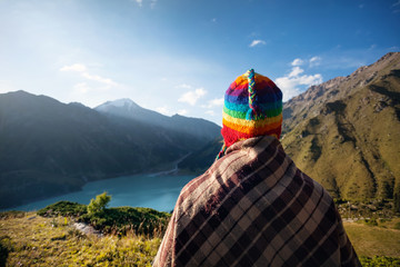 Tourist woman in rainbow hat at the mountains - obrazy, fototapety, plakaty
