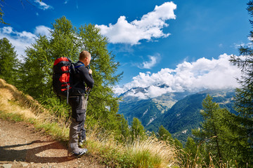 hiker in the Apls mountains. Trek near Matterhorn mount. hiker stands on the trail, looks at the valley, and drinks water from the H2O system