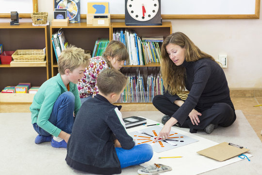 Montessori teacher helping students in classroom