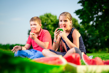 Boy and a girl eating watermelon on a sunny day