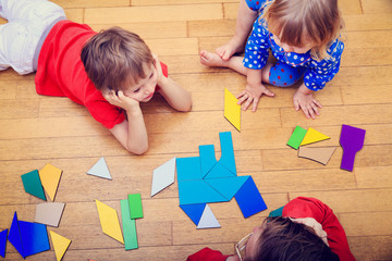 teacher and kids playing with geometric shapes, early learning
