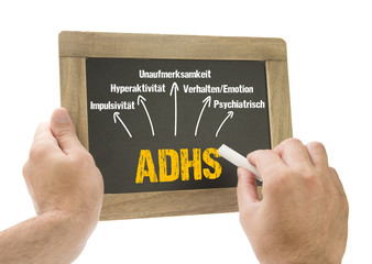 Hand schreibt ADHS Symptome auf Kreidetafel
