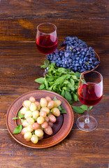 Two glasses of wine with grapes on a wooden background