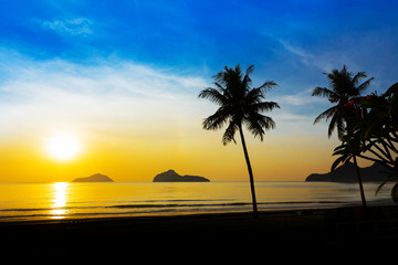 Fototapeta na wymiar Sunrise at sea with islands and coconut trees.